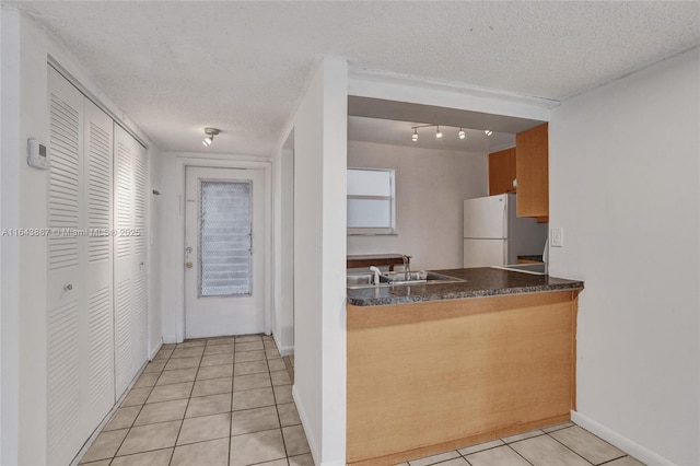 kitchen featuring light tile patterned floors, sink, a textured ceiling, and white fridge