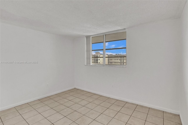 tiled empty room featuring a textured ceiling