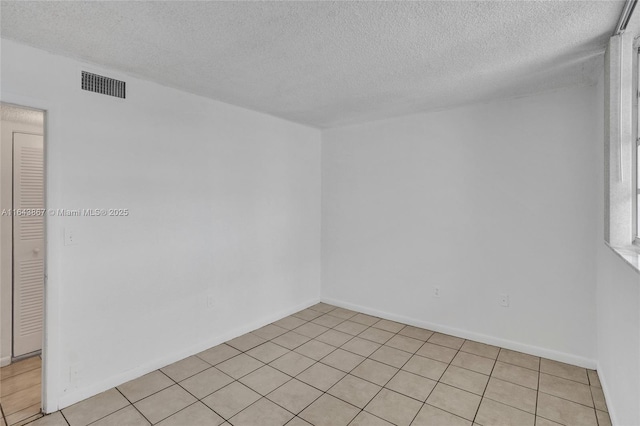 unfurnished room featuring light tile patterned floors and a textured ceiling