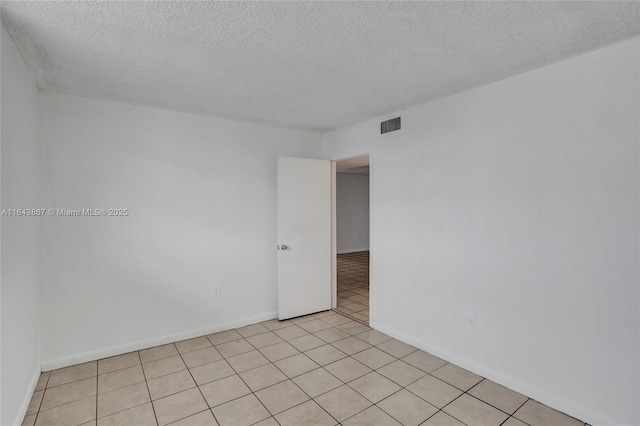 unfurnished room with a textured ceiling and light tile patterned floors