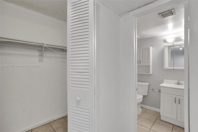 bathroom featuring vanity, tile patterned floors, a textured ceiling, and toilet