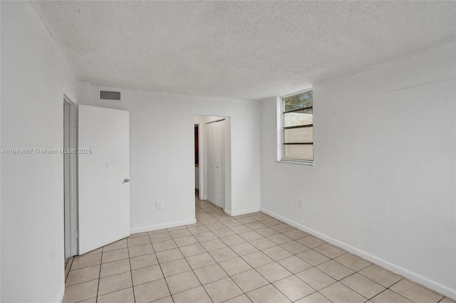 empty room with light tile patterned floors and a textured ceiling