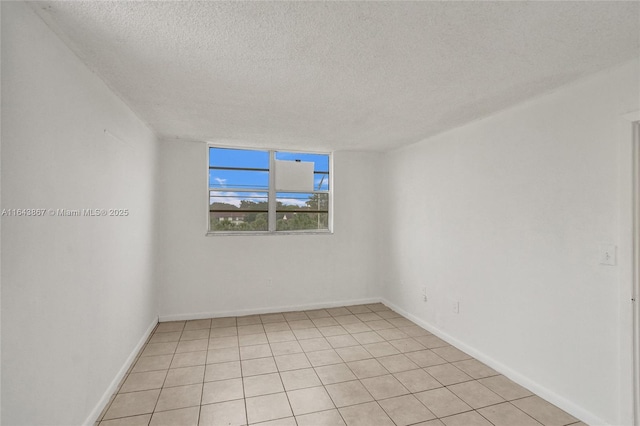 spare room with a textured ceiling and light tile patterned floors