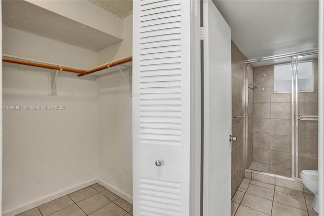 bathroom with tile patterned flooring, an enclosed shower, and toilet