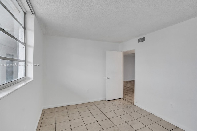 unfurnished room with light tile patterned floors and a textured ceiling