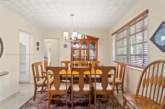 dining area featuring a textured ceiling, an inviting chandelier, and light tile patterned floors