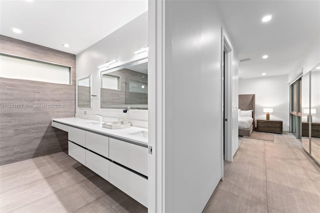 bathroom with tile walls, dual vanity, and tile patterned floors