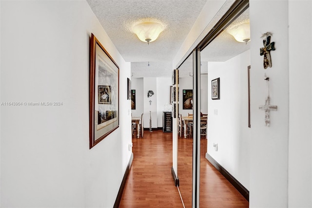 hallway with a textured ceiling and dark wood-type flooring