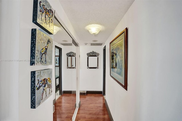 hallway featuring a textured ceiling and dark hardwood / wood-style floors