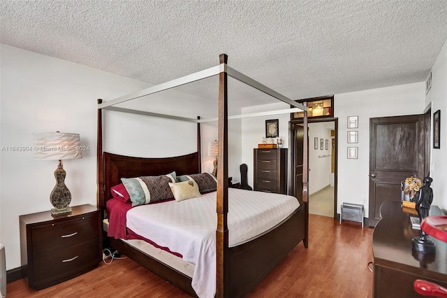 bedroom with a textured ceiling and wood-type flooring