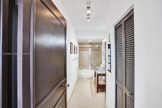 hallway with a textured ceiling and light tile patterned floors