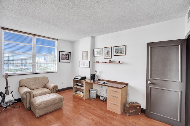 home office with a textured ceiling and light hardwood / wood-style floors