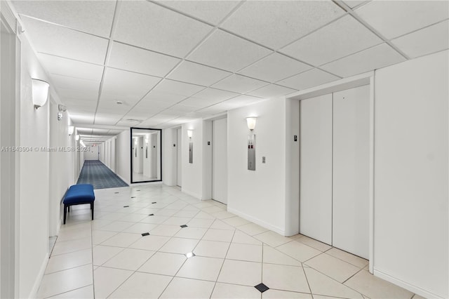 interior space with light tile patterned floors, elevator, and a drop ceiling