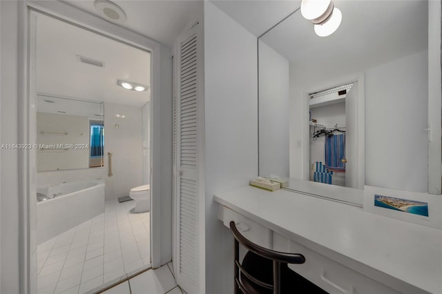 bathroom with tiled bath, toilet, vanity, and tile patterned floors