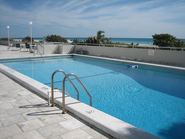 view of swimming pool with a patio and a water view