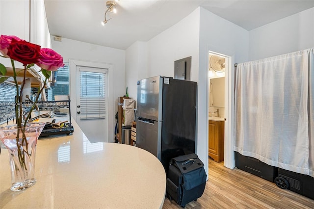 kitchen with a wealth of natural light, stainless steel refrigerator, white cabinets, and light wood-type flooring