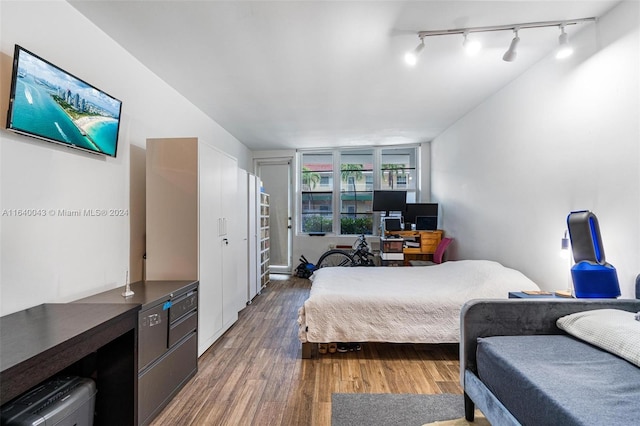 bedroom with track lighting and dark hardwood / wood-style floors