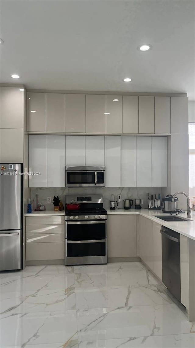 kitchen with gray cabinets, tasteful backsplash, sink, light tile patterned flooring, and stainless steel appliances