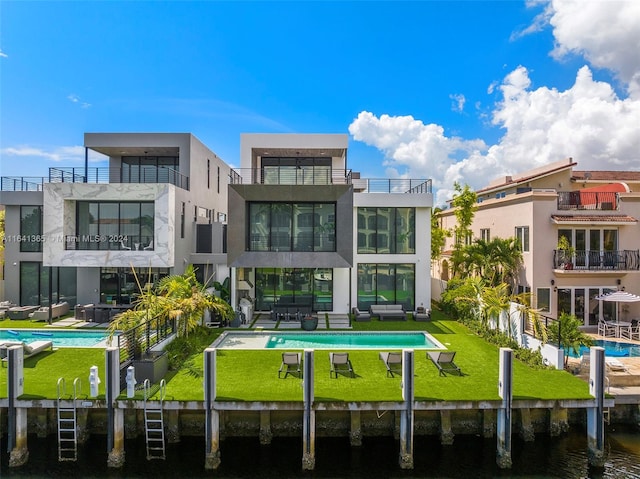 rear view of property with a balcony, a water view, a patio area, and a yard