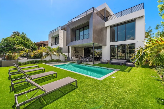 rear view of property featuring a patio area, a balcony, and a lawn