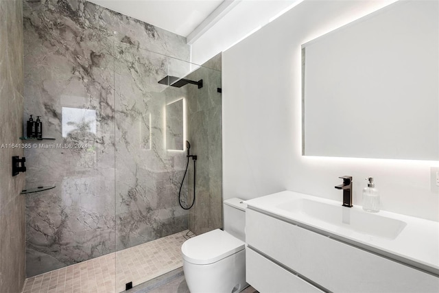 bathroom featuring toilet, tiled shower, and vanity