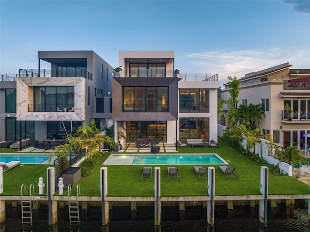 rear view of property featuring a balcony and a lawn