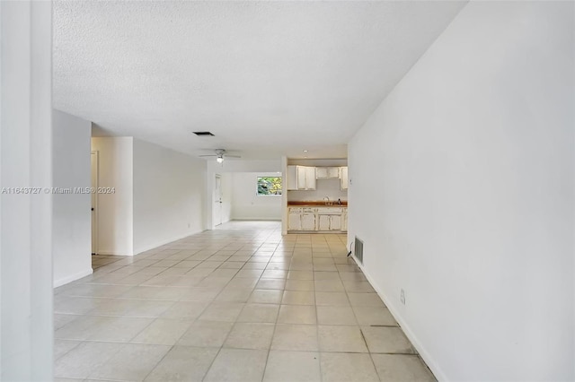 unfurnished room featuring a textured ceiling, ceiling fan, sink, and light tile patterned floors