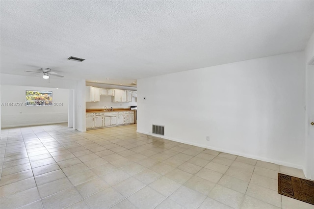 unfurnished living room featuring ceiling fan, sink, and a textured ceiling