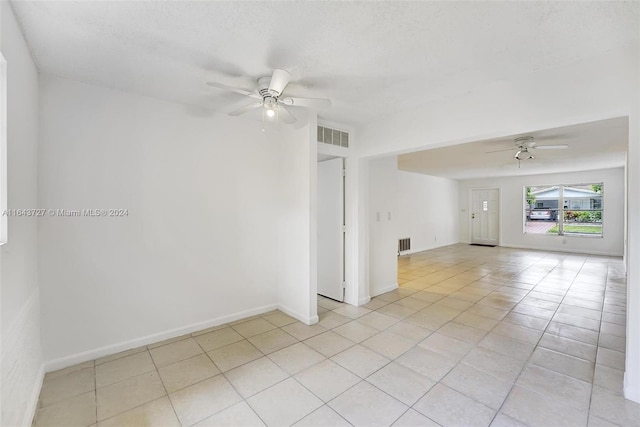 tiled empty room with a textured ceiling and ceiling fan