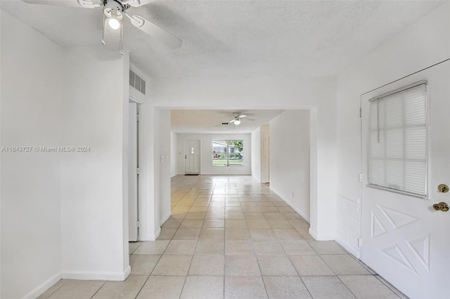 corridor with a textured ceiling and light tile patterned flooring