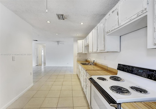 kitchen with a textured ceiling, light tile patterned flooring, sink, white electric range oven, and white cabinets