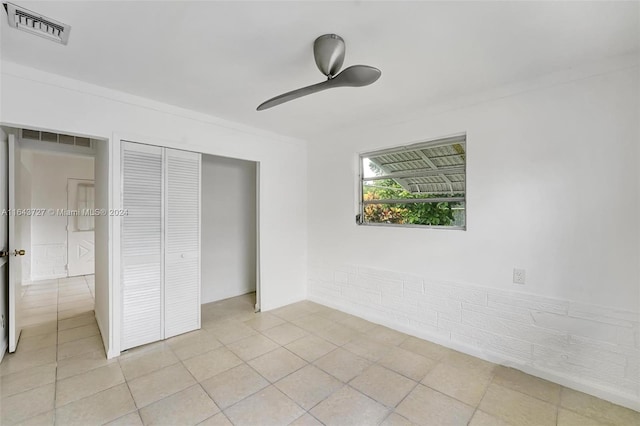 unfurnished bedroom featuring light tile patterned floors, ceiling fan, and a closet