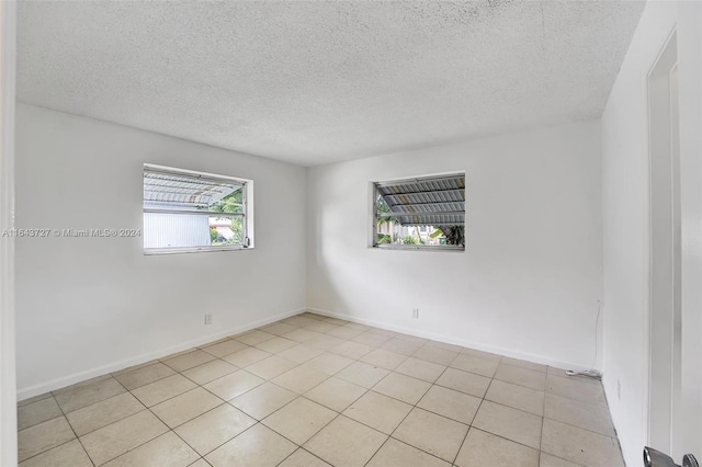 unfurnished room featuring light tile patterned flooring and a textured ceiling