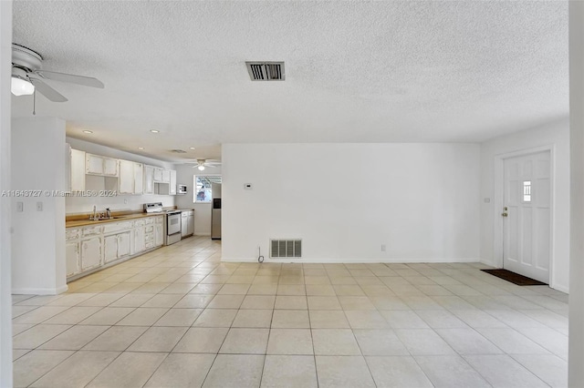 unfurnished living room featuring ceiling fan, sink, light tile patterned flooring, and a textured ceiling