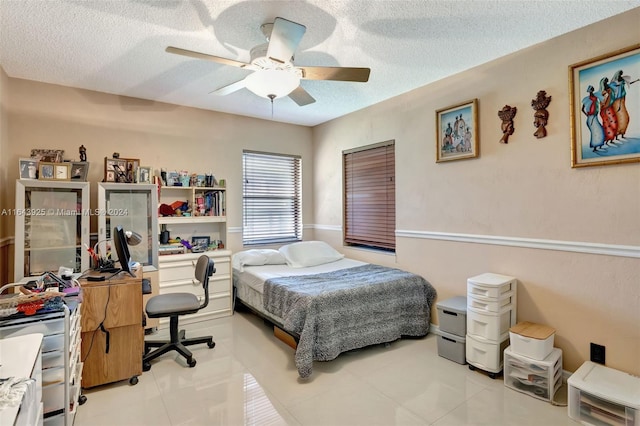 bedroom featuring light tile patterned floors, ceiling fan, and a textured ceiling