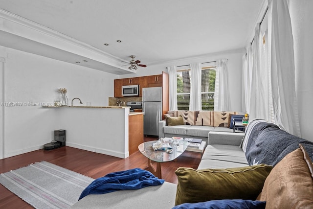 living room with ceiling fan, baseboards, and wood finished floors