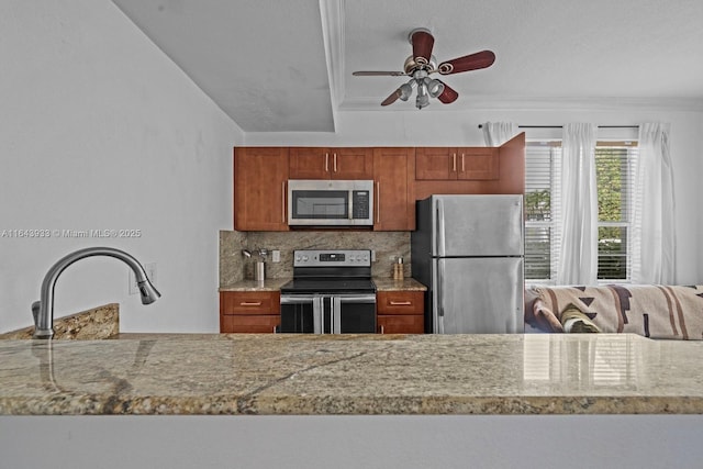 kitchen with light stone countertops, stainless steel appliances, a ceiling fan, brown cabinets, and tasteful backsplash