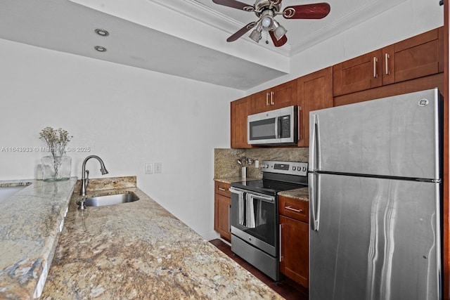 kitchen featuring light stone counters, crown molding, stainless steel appliances, tasteful backsplash, and a sink