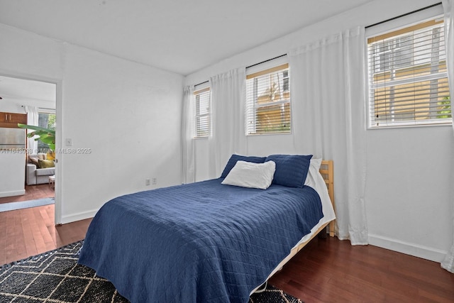 bedroom featuring multiple windows, baseboards, and wood finished floors