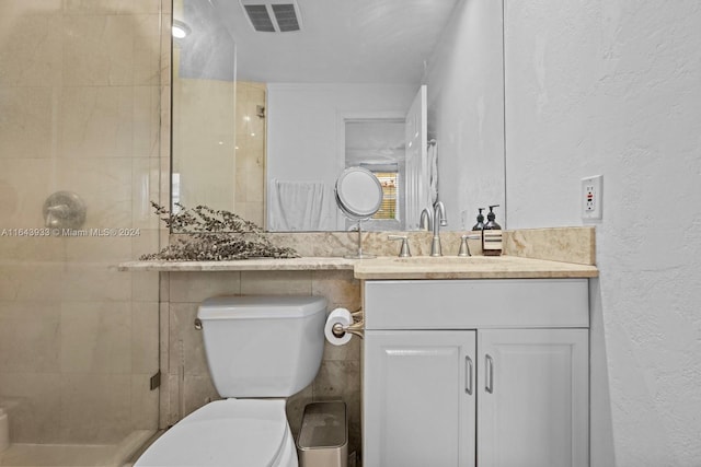 bathroom featuring tile walls, toilet, a tile shower, and vanity