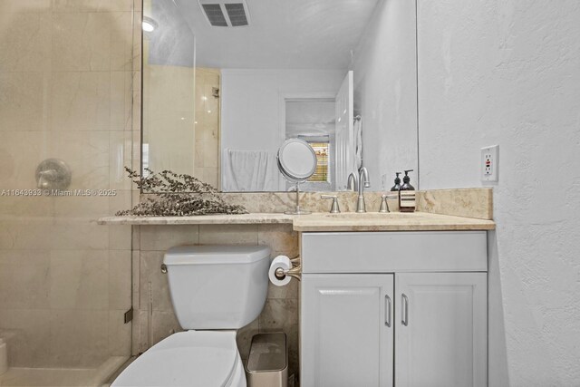 bathroom with a stall shower, visible vents, a textured wall, toilet, and vanity