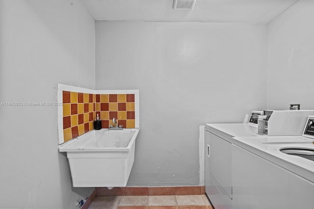 washroom featuring a sink, light tile patterned floors, visible vents, and washer and dryer