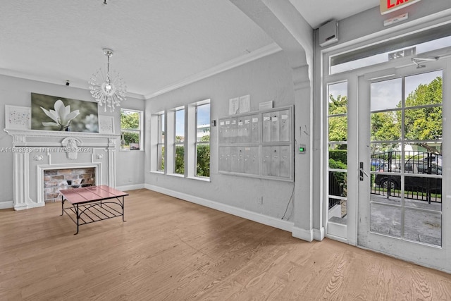 doorway featuring a textured ceiling, ornamental molding, light wood-type flooring, and a fireplace