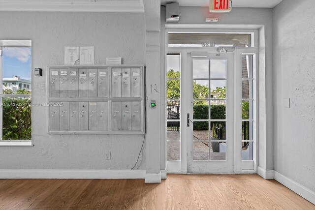 entryway with mail area, baseboards, wood finished floors, and a textured wall