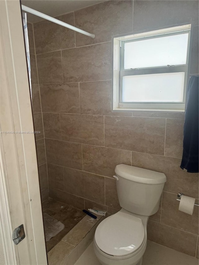 bathroom featuring tile walls, tiled shower, and toilet