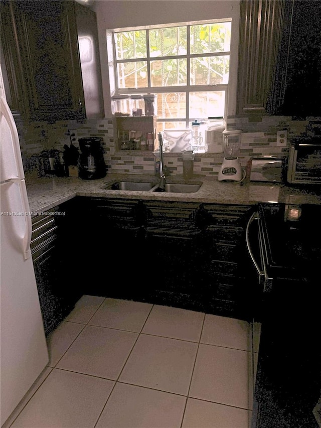 kitchen featuring decorative backsplash, tile patterned flooring, white refrigerator, sink, and stove