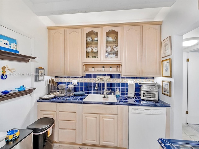 kitchen featuring sink, light brown cabinets, light tile patterned floors, tile counters, and white dishwasher