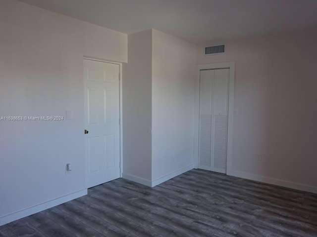 unfurnished bedroom featuring a closet and dark wood-type flooring