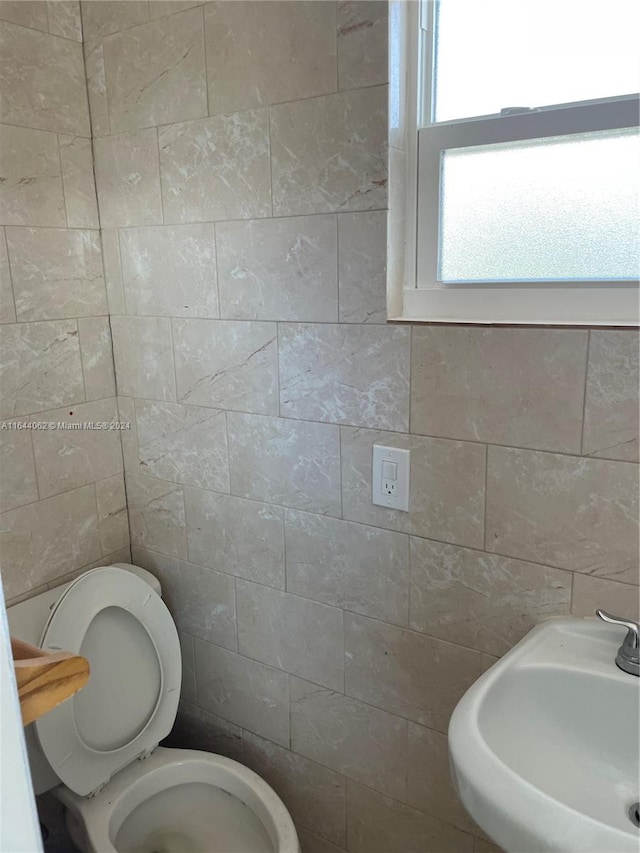 bathroom featuring sink, tile walls, and toilet