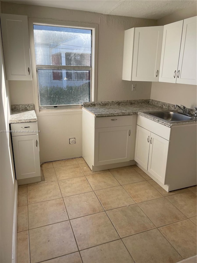 kitchen featuring white cabinetry, a textured ceiling, light tile patterned floors, and sink